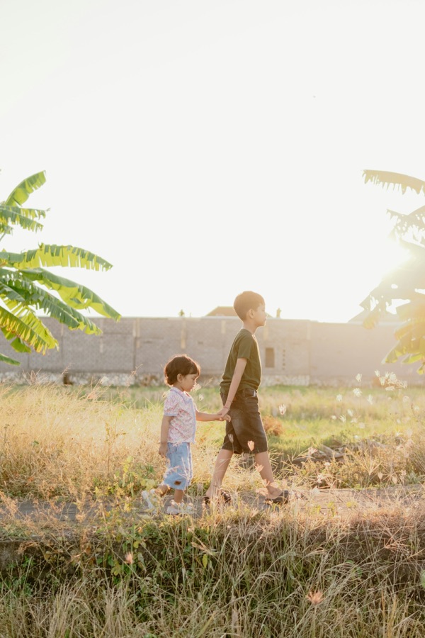 Two children walking through a golden field in warm evening light